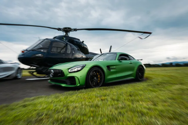 A green Mercedes-AMG photographed beside a helicopter