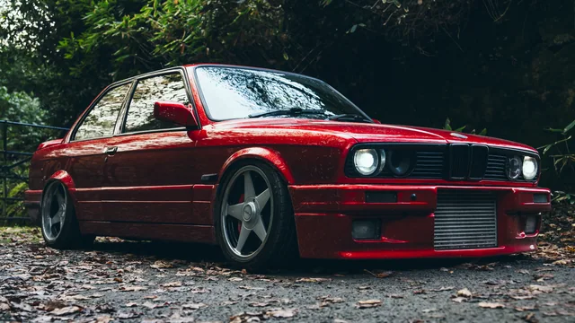 A red BMW photographed low against woodland
