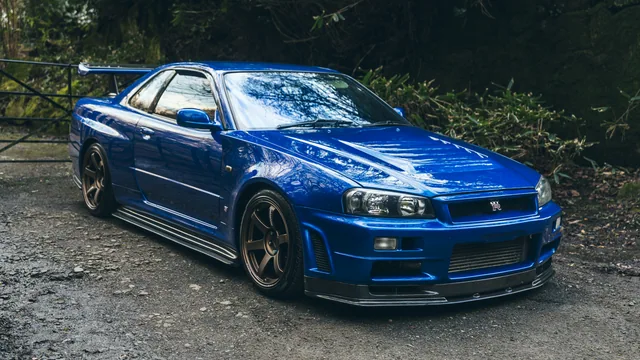 A blue Nissan Skyline photographed against woodland