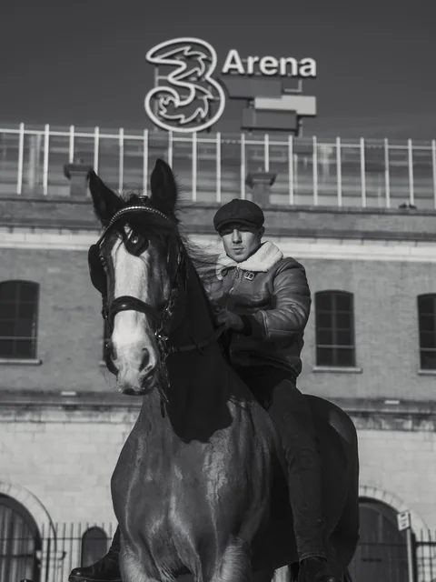 A black and white campaign photograph with a horse outside the 3Arena