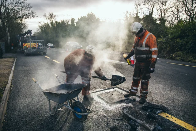 Road crew working together with steam rising from the surface