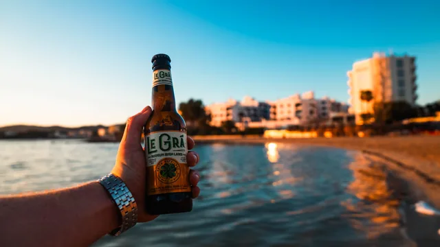A bottle held above the water against the Ibiza coastline