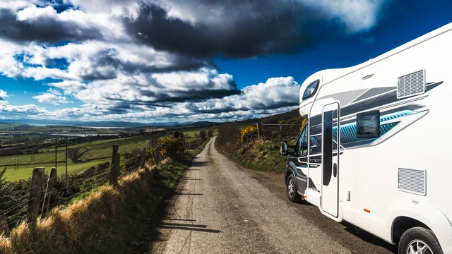 A motorhome on a rural road beneath a dramatic sky