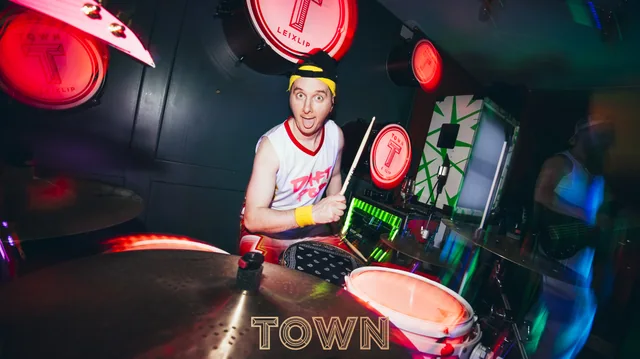 A DJ performing under colourful venue lighting