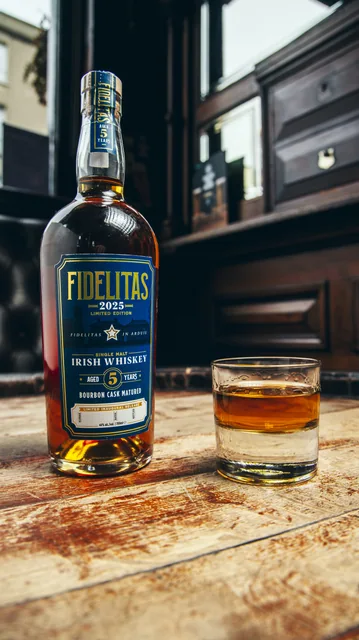 A whiskey bottle and glass in soft window light