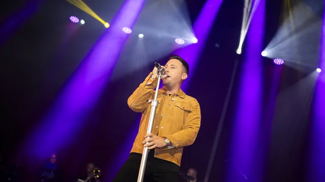 Nathan Carter singing under purple stage lights