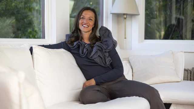 A smiling woman seated on a white sofa