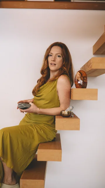 A woman in a green dress seated on a staircase