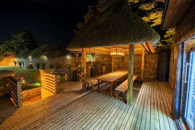 An illuminated covered terrace and outdoor seating at night